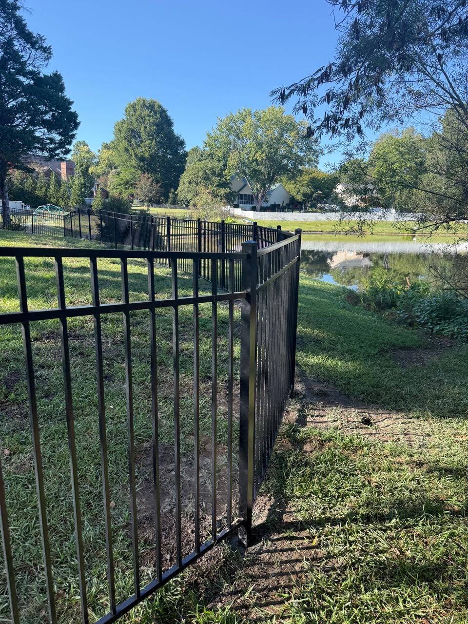 Corner of a black aluminum fence beside a pond
