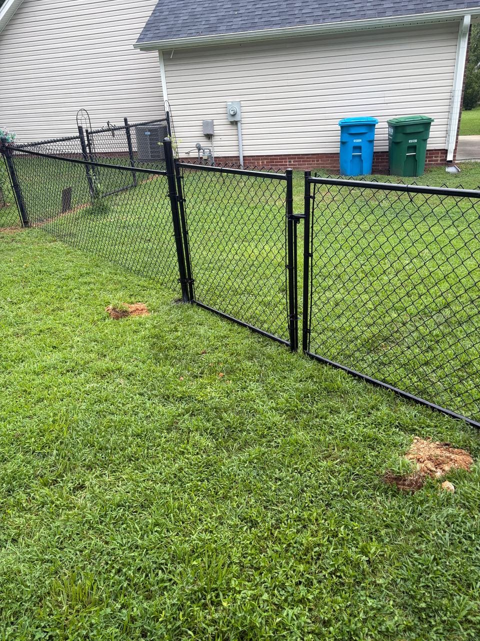 Black chain link fence with a walk gate and a double gate beside a house